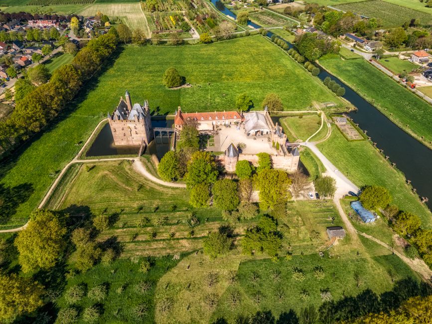 A stunning aerial view of a historic castle surrounded by lush greenery and farmland.