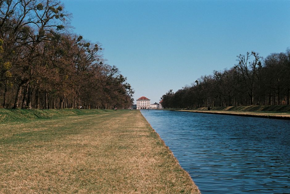 Serene view of Nymphenburg Palace canal surrounded by trees in Munich, Germany.