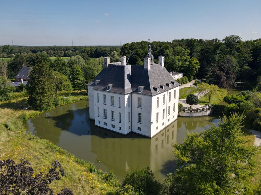 Historic Schloss Gartrop, a beautiful white castle, surrounded by a lush landscape and serene moat.